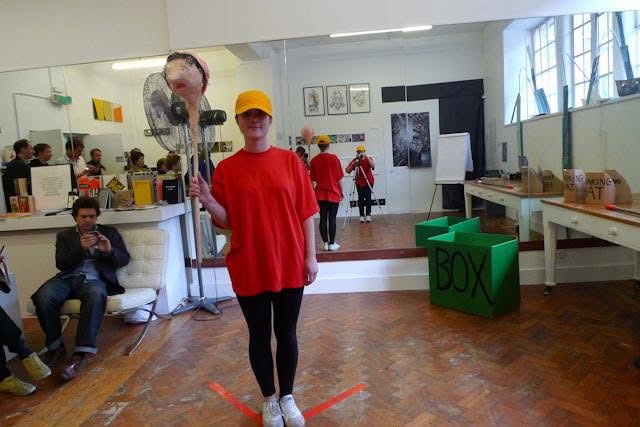 Sluice Art Fair — the performer holding a sculpted puppet head on a stick beside a large fan