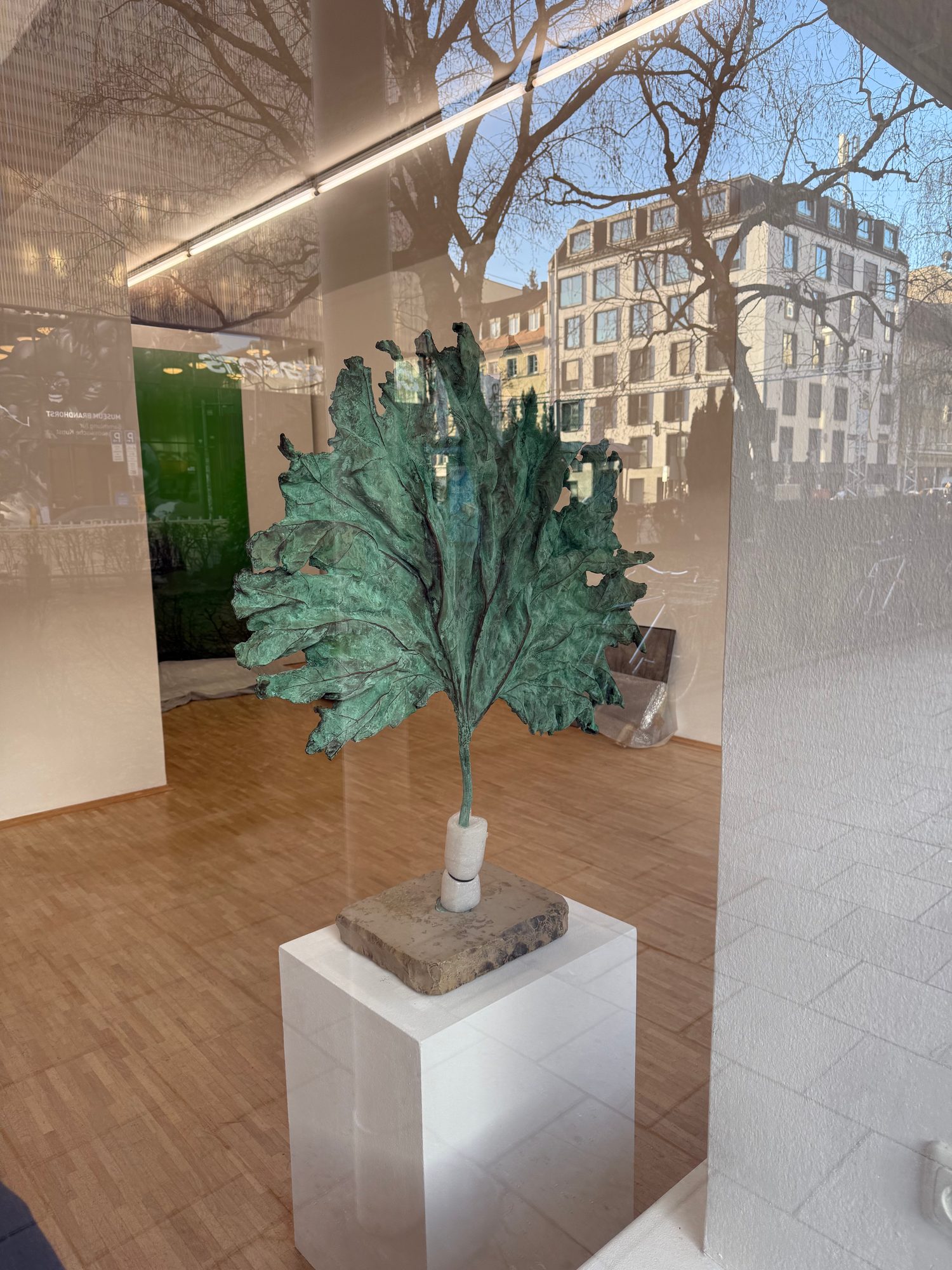 Leaf sculpture on a pedestal seen through the gallery window