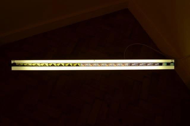 Sluice Art Fair — a long strip of film lit by a horizontal light bar in a darkened room