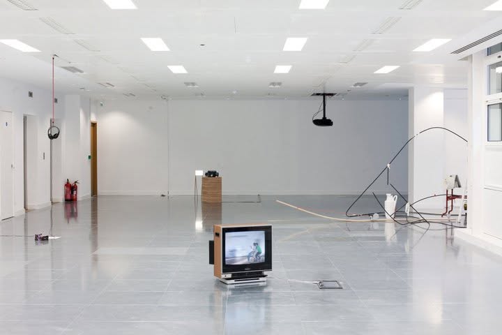 An older television playing a film on the floor beside suspended headphones
