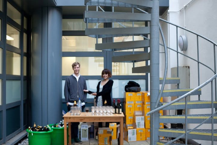 Two people behind a drinks table beside stacked Cobra crates at the exhibition opening