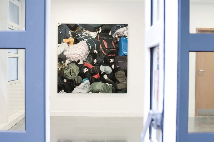 A wall photograph of a crowd seen from above, viewed through a blue doorway