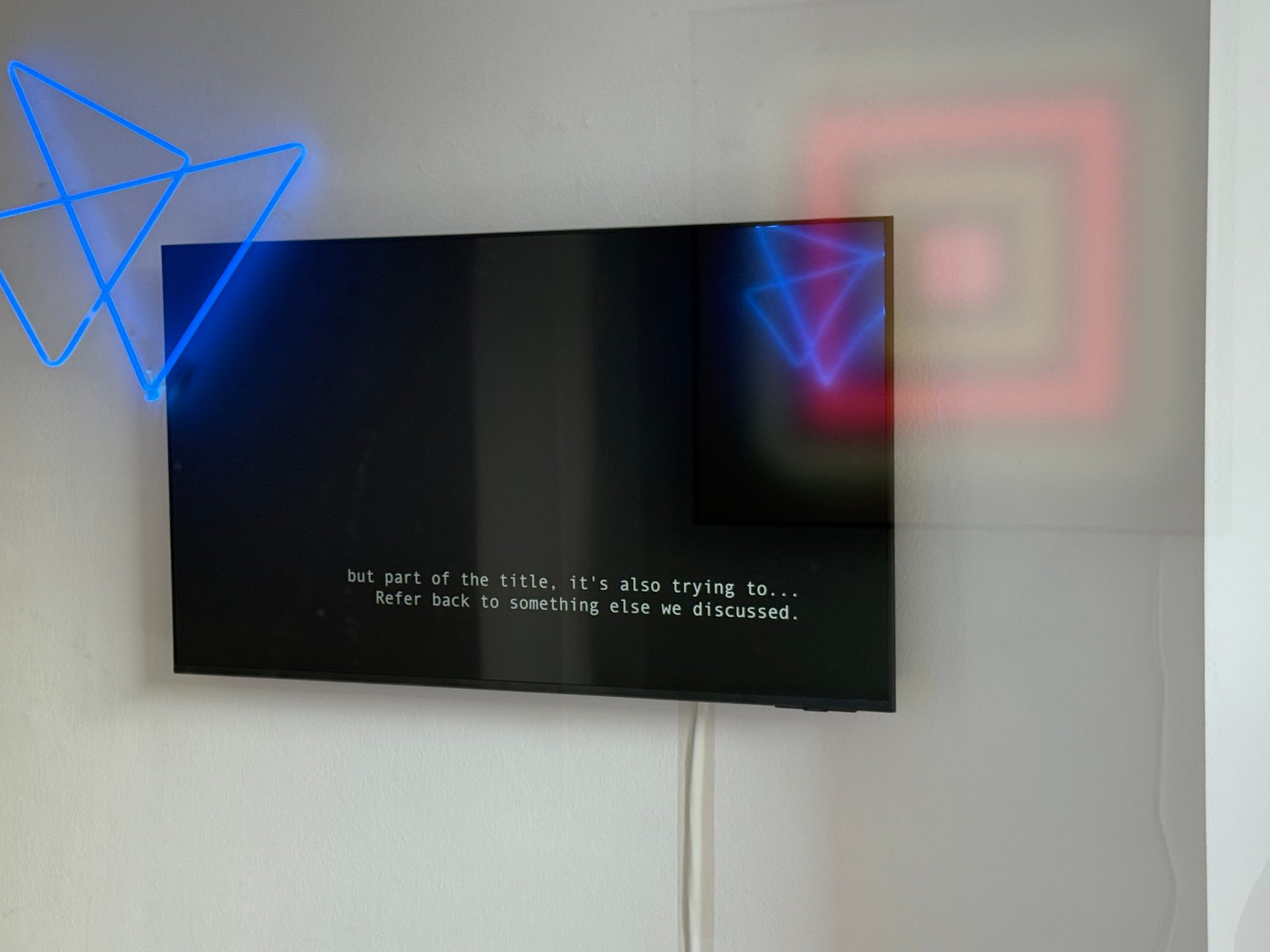 Wall-mounted screen beside a blue neon shape